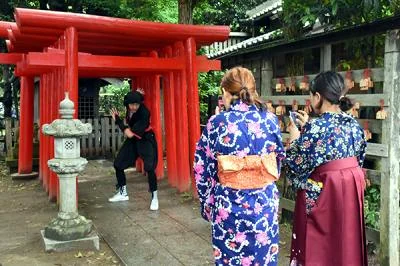 衣装を着て朱の鳥居の前で撮影を楽しむ様子